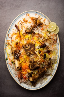 Mutton or lamb biriyani with basmati rice, served in a bowl over moody background.