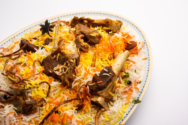 Mutton or lamb biriyani with basmati rice, served in a bowl over moody background.