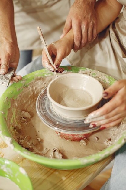 Mutual creative work. Hands creating a bowl on a pottery wheel in a clay studio.