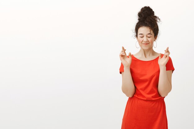 Free photo my wish definitely come true. grinning happy european woman in red dress with hair combed in bun