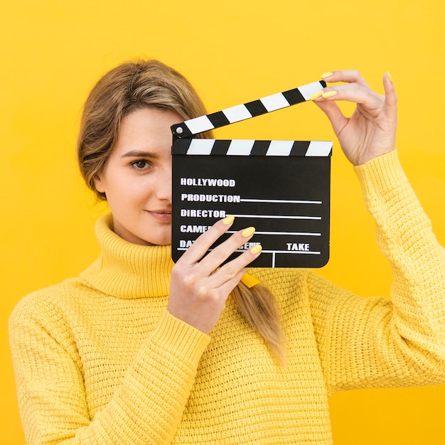 Free photo mysterious woman holding clapboard