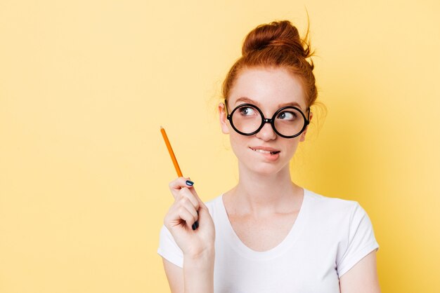 Mystery ginger woman in eyeglasses bites her lip with pencil