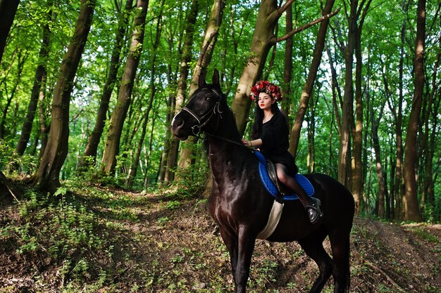 花輪の神秘的な女の子は木の馬で黒で着る