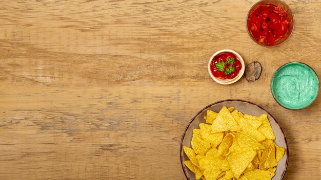 Nachos and different organic sauces on wooden table