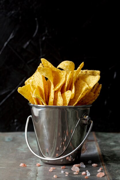 Nachos in metallic bucket against black background