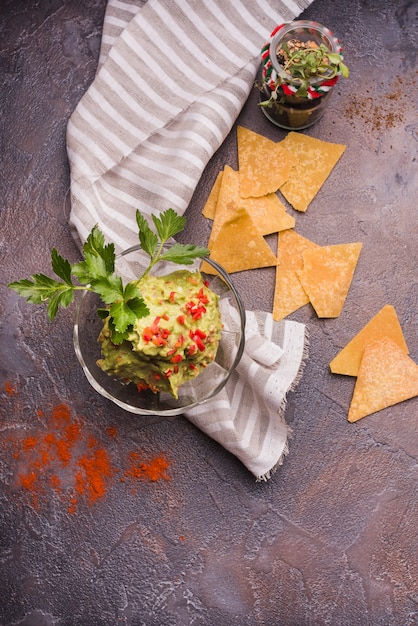 Foto gratuita nachos vicino guacamole in ciotola e tovagliolo