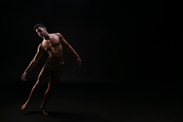 Free photo naked athletic bent man standing on black background