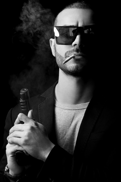Бесплатное фото Голая мужская модель в тени, как гангстер с оружием