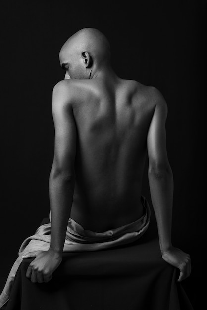 Naked man posing on chair black and white medium shot