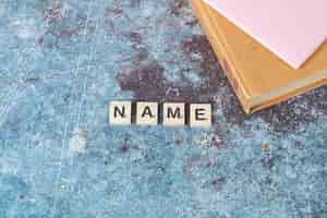 Free photo name writing with black letters on wooden dices with an old book around. high quality photo