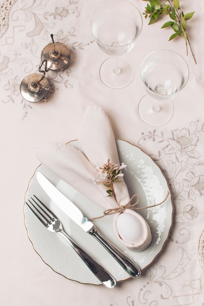 Free photo napkin and cutlery on plate near glasses and plant