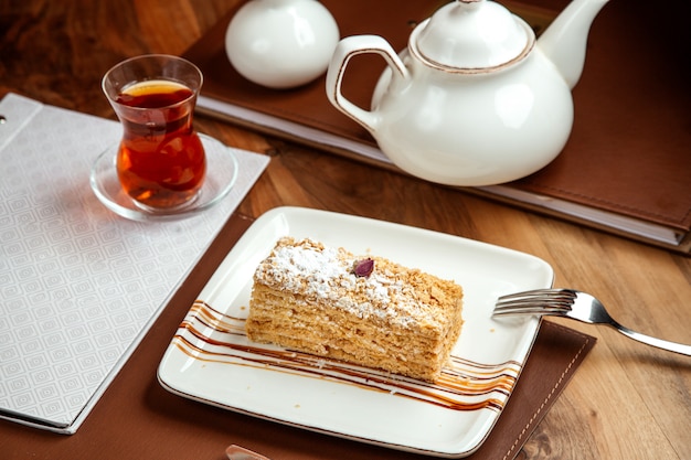 napoleon cake with butter cream sugar powder and dark tea on table