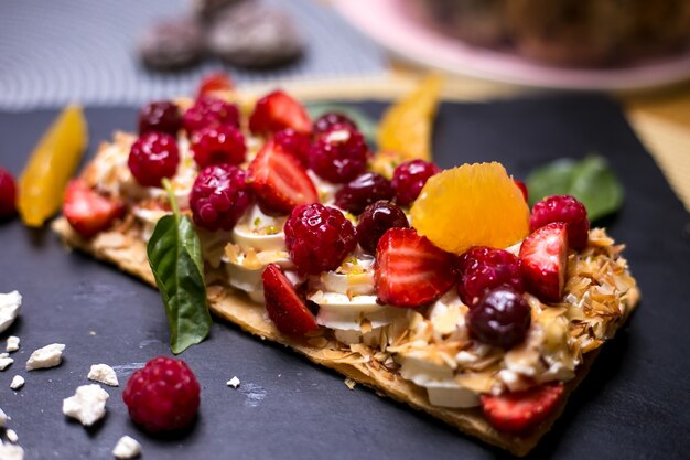 Napoleon tart with cream raspberry orange cherry marshmallows mint side view