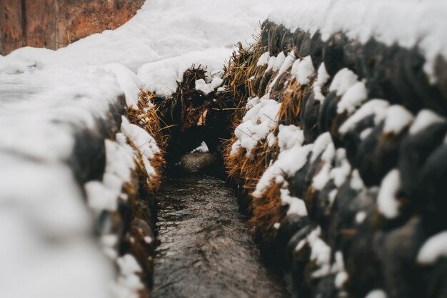 Narrow pathway between stacks of hay covered in snow