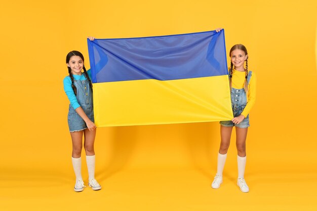 National identity concept. ukrainian kids. girls with blue and yellow flag. patriotic education. happy independence day. children hold ukrainian flag. patriotism respect and love to motherland.