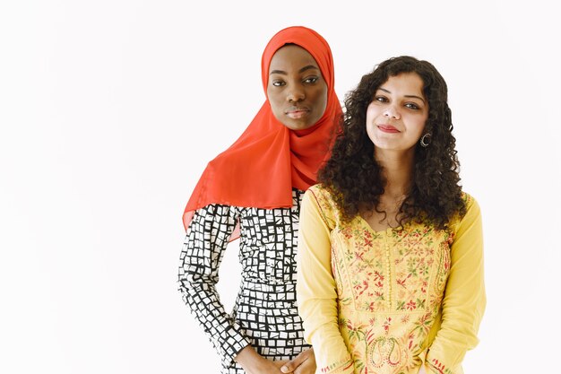 Nations friiendship. Afrcian and Indian women in traditional clothes. Isolated, white studio.