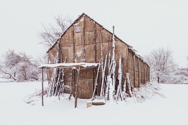 冬の間白い雪で覆われた地面を持つネイティブアメリカンのロングハウス