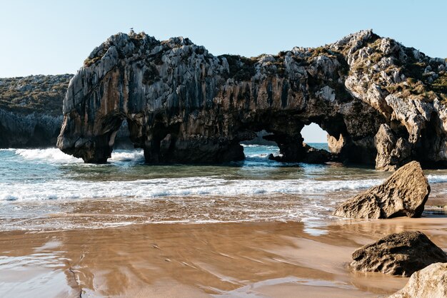 Natural arch from rocks in the water near the shore on a clear day