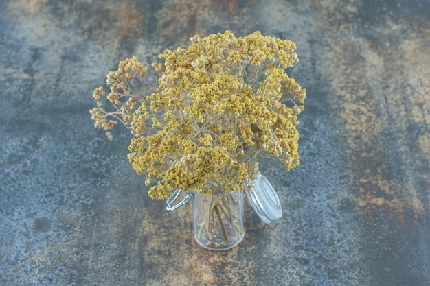 Natural dried yellow flowers in glass jar.