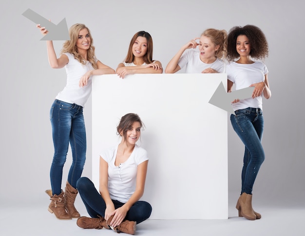 Foto gratuita ragazze naturali con diverse nazionalità che mostrano sulla lavagna bianca