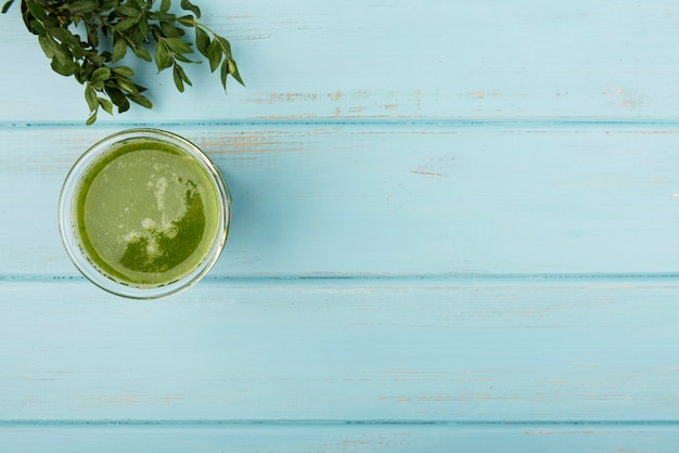 Natural green smoothie in glass on wooden background