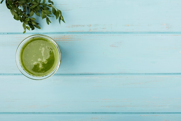 Натуральный зеленый коктейль из стекла на деревянном фоне