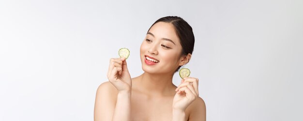 Natural homemade fresh cucumber facial eye pads facial masks Asian woman holding cucumber pads and smile relax with natural homemade