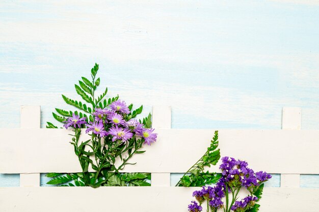 Natural leaves and flowers along white fence