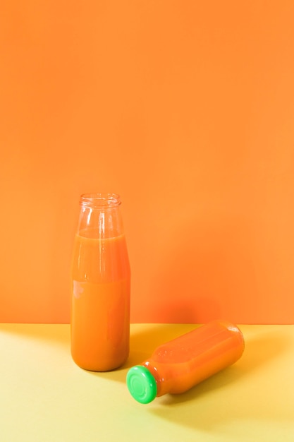 Natural orange smoothie in bottle on table