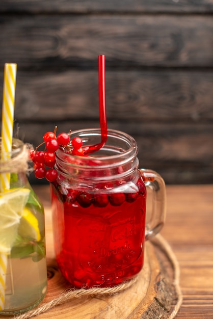 Natural organic fuit juices in bottles served with tubes on a wooden cutting board