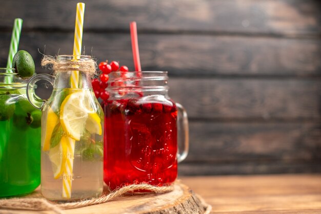 Natural organic fuit juices in bottles served with tubes on a wooden cutting board