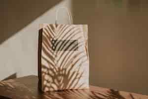 Free photo natural paper bag with palm leaves shadow