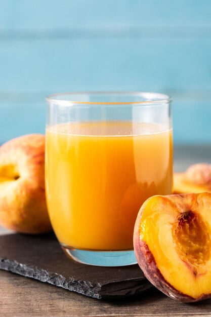 Natural peach juice in glass on wooden table