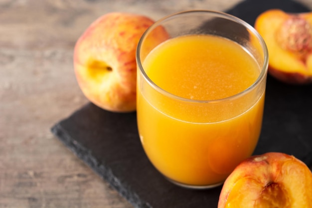 Натуральный персиковый сок в стакан на деревянный стол
