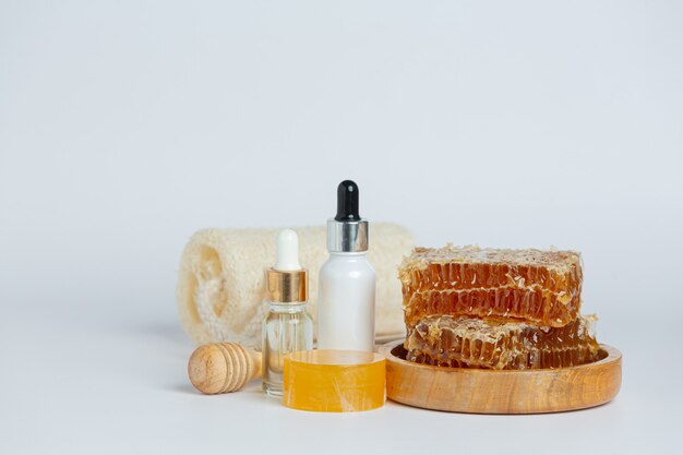 Natural skin care soap and serum with honey and honeycomb laid on white surface.