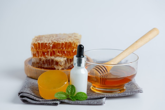 Natural skin care soap and serum with honey and honeycomb laid on white surface.