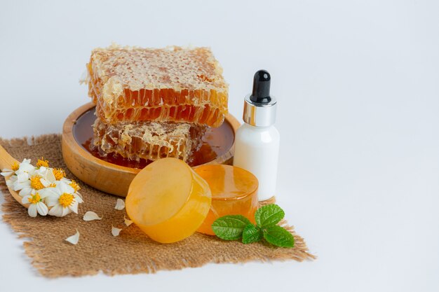 Natural skin care soap and serum with honey and honeycomb laid on white surface.