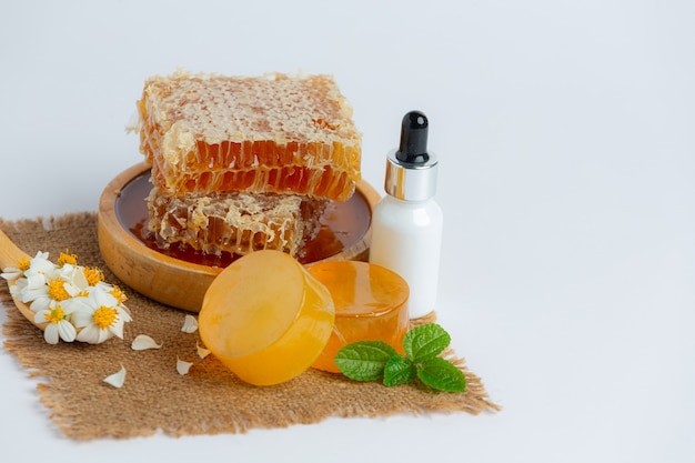 Natural skin care soap and serum with honey and honeycomb laid on white surface.