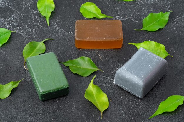 Natural soap and green leaves on dark gray background