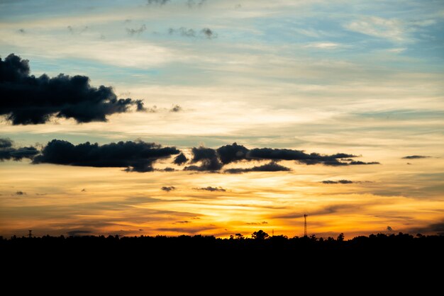 フィールドまたは草原の自然日没の日の出。明るい劇的な空と暗い地面。