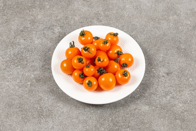 Natural tomatoes in plate, on the marble.