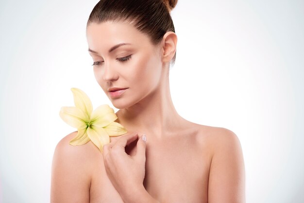 Natural young woman with lily on the arm