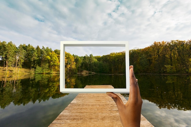 Nature landscape with hand holding frame