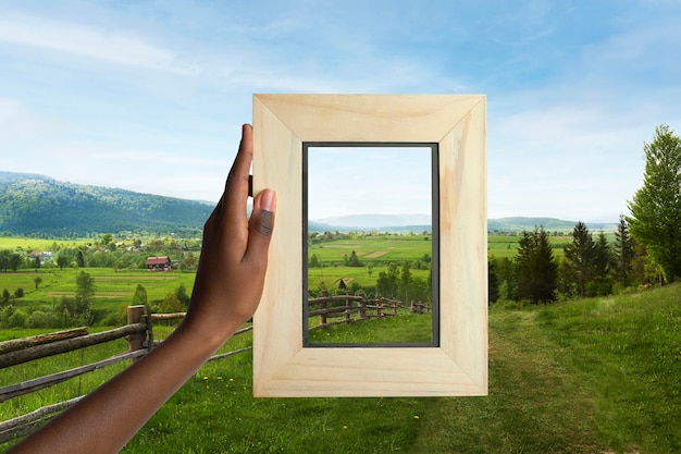 Nature landscape with hand holding frame