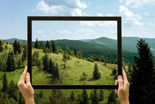 Nature landscape with hand holding frame