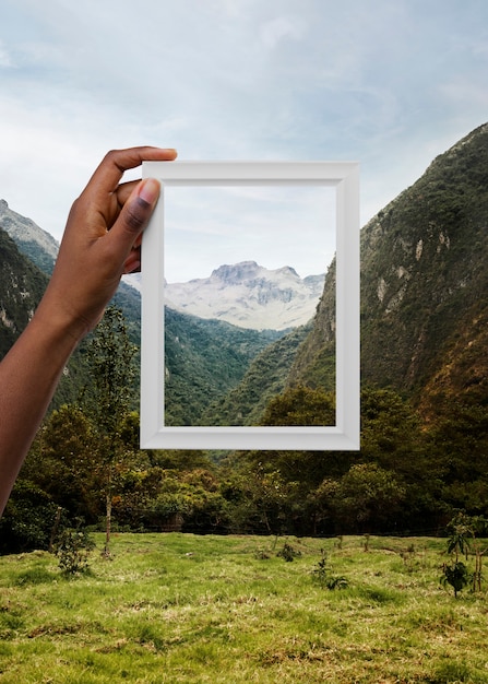 Free photo nature landscape with hand holding frame