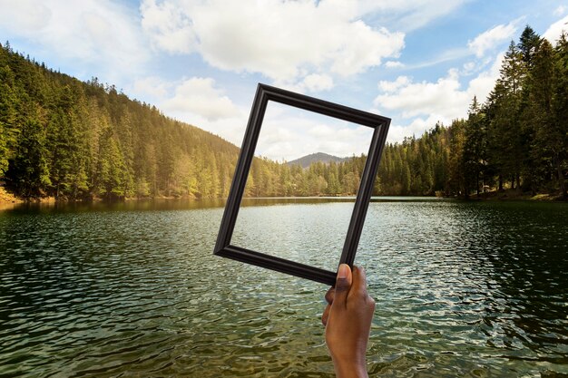 Nature landscape with hand holding frame