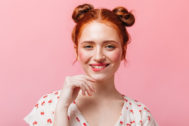 Free photo naughty red-haired lady with bright makeup winks and smiles on pink background.