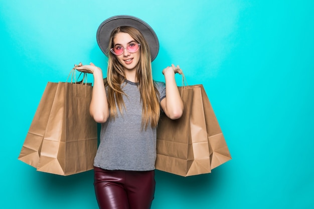 Naughty shopping woman smiling and wearing a hat isolated over green background