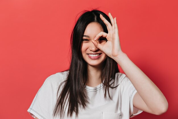 白いトップのいたずらな女性は笑ってOKサインを示しています